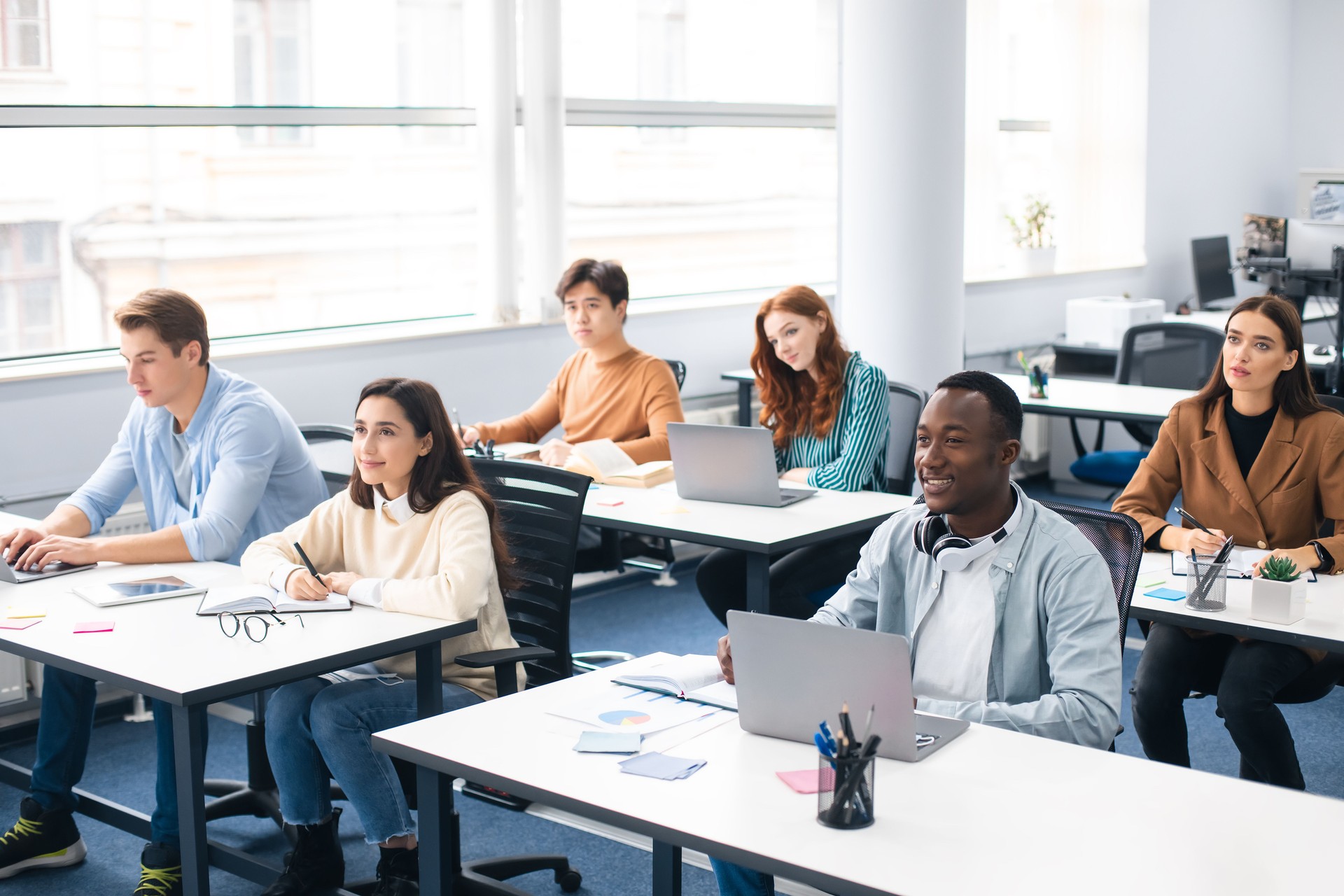Group of international people listening to teacher at classroom